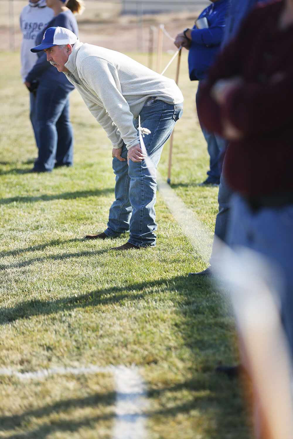 Brian Faubert walks the sideline fence forward as he watches the Kaycee offense